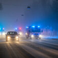 Altstadt mit Kirche bei Schneewetter, Einsatzfahrzeuge der Feuerwehr mit Blaulicht auf der Straße.