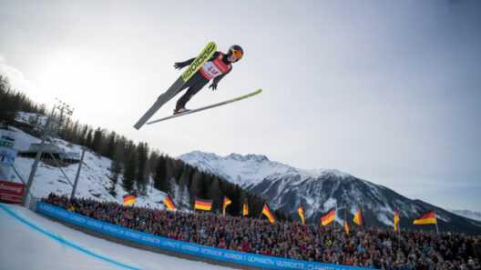 Altstadt mit Kirche, Szenerie mit Skispringer bei sportlichem Event in den Alpen.