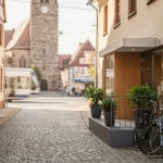 Altstadtgasse mit Kirche, Kopfsteinpflaster und Fahrradständern in einer deutschen Stadt.